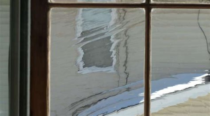 Why does old glass look wavy?